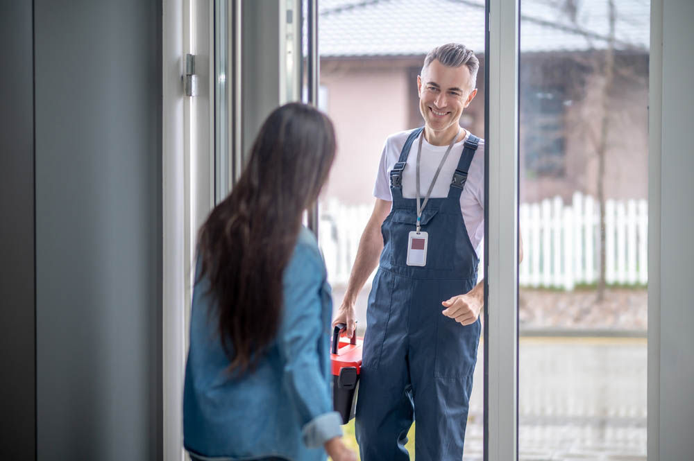 plumber with suitcase of tools and woman opening door