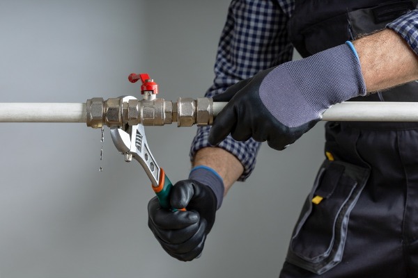 plumber repairing leaking water pipe valve