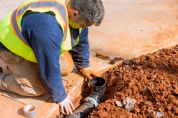 plumber repairing underground sewer line connection